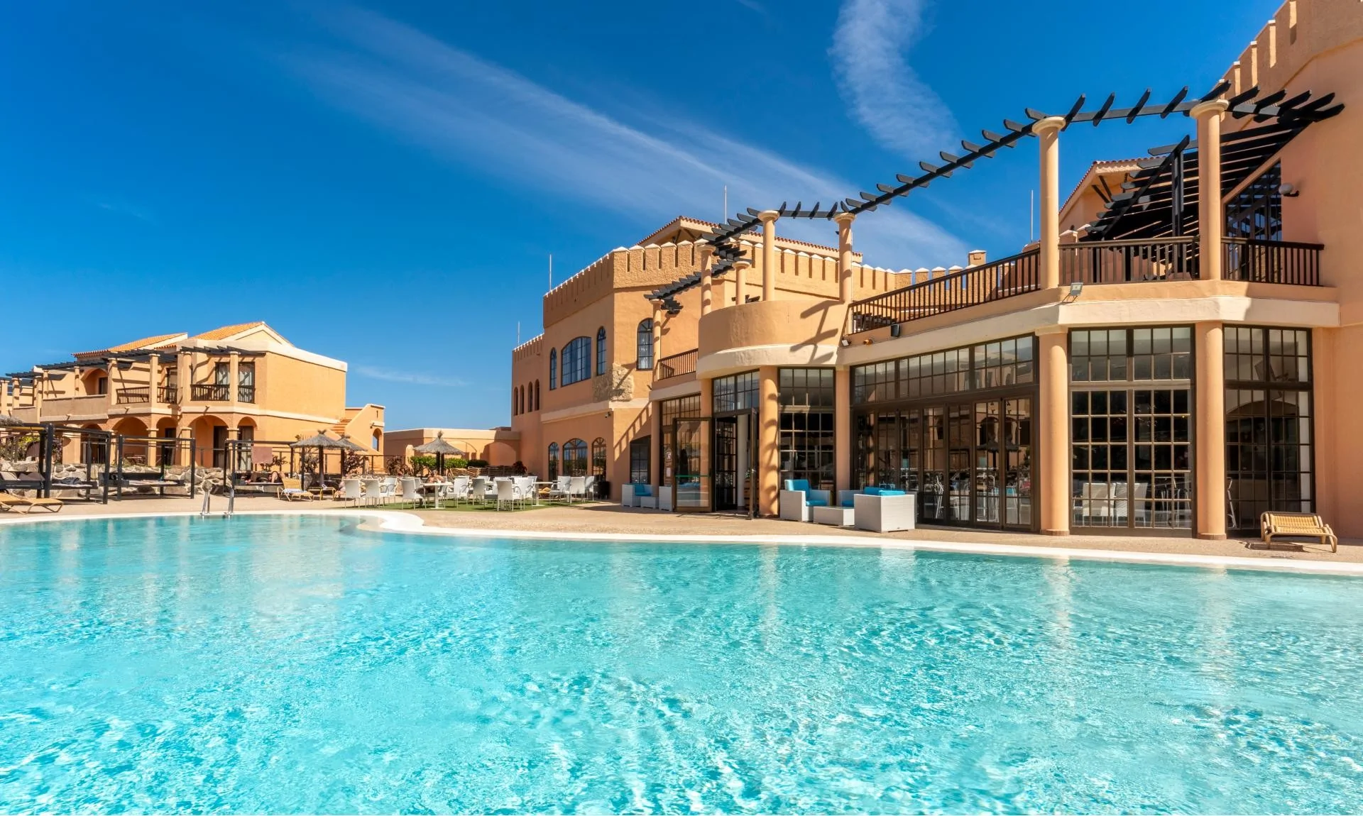 Hotel pool with terracotta building and blue sky
