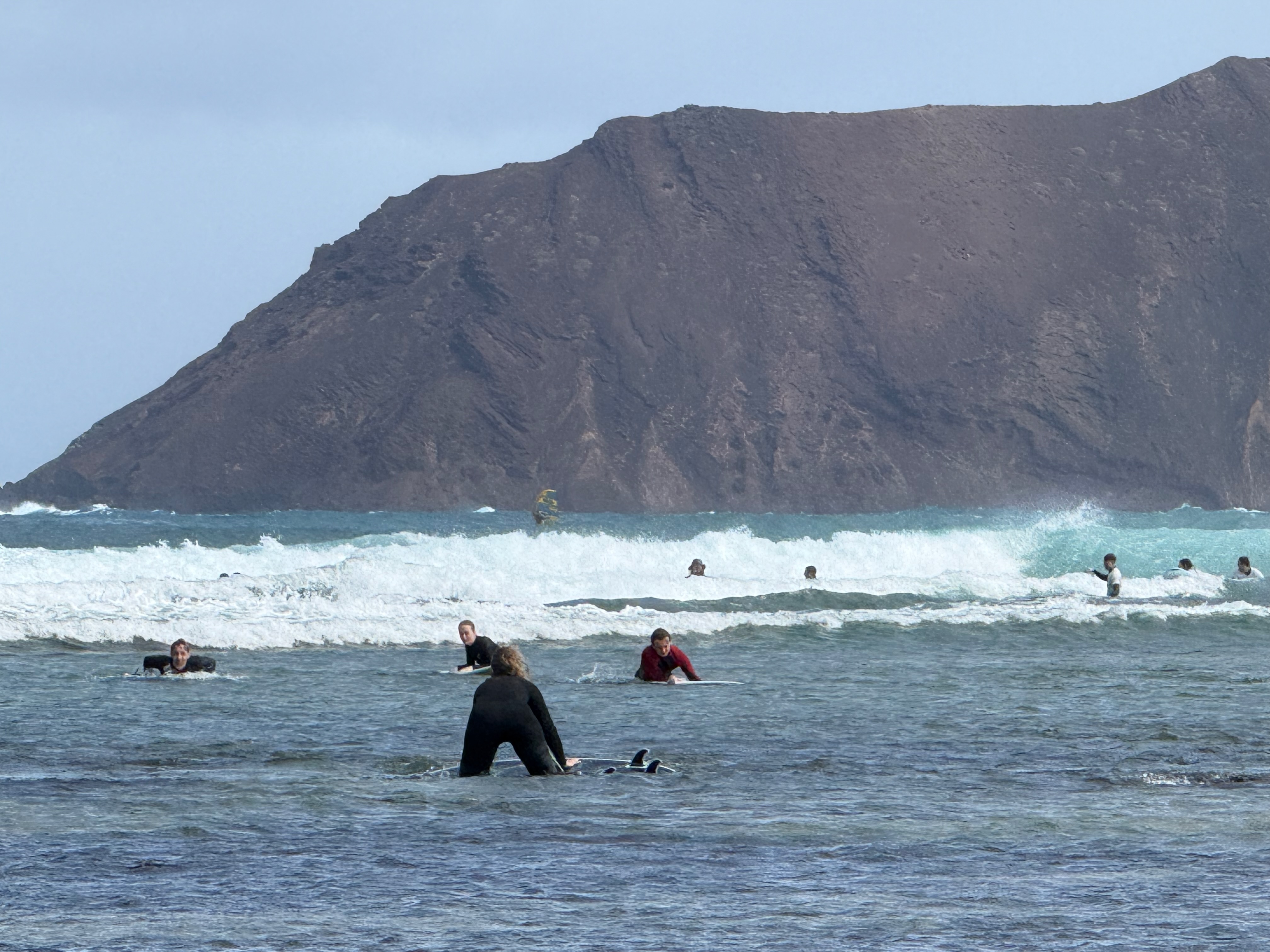 Surfers paddling out toward Lobos cliff