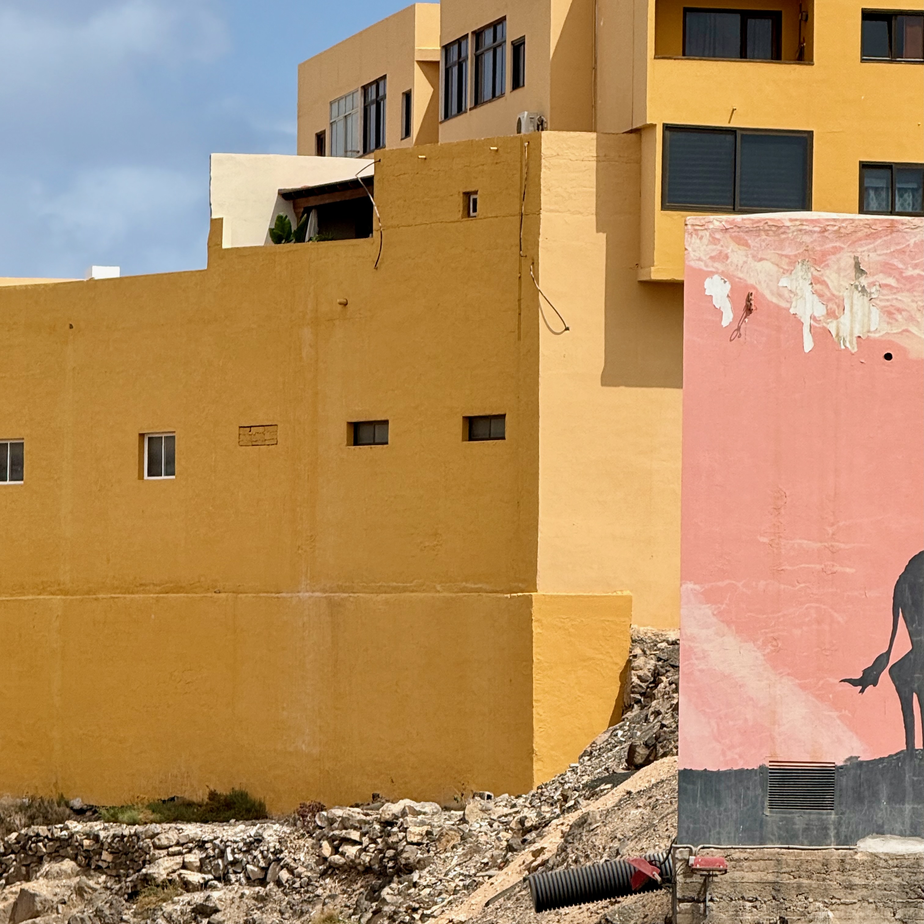 Ochre buildings and a faded pink mural with a surfer silhouette